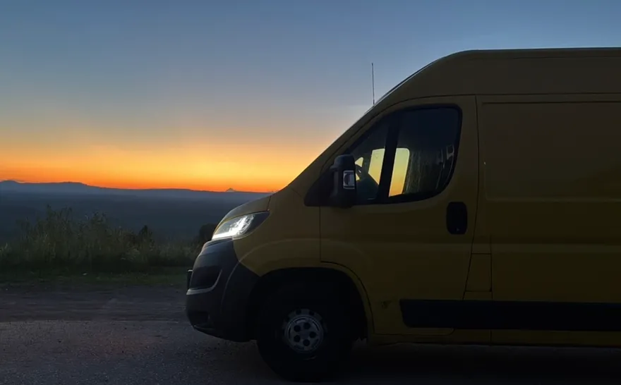 NB-Palveluiden keltainen muuttoauto auringonlaskussa